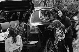 A mother loads the boot of her car with her two young daughters.
