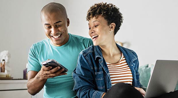 Couple near laptop and using mobile