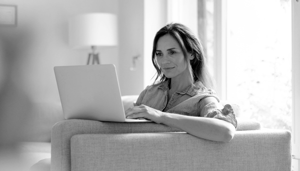 A woman works on her laptop while relaxing on her lounge.
