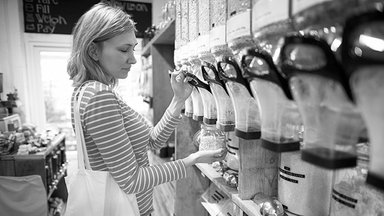A woman stands in a bulk food store shopping for waste-free groceries.
