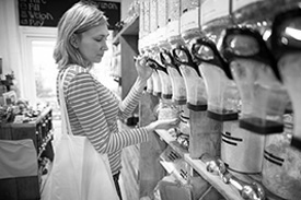 A woman stands in a bulk food store shopping for waste-free groceries.