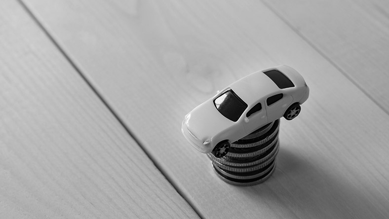 A toy car placed upon a pile of coins.