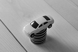 A toy car placed upon a pile of coins.