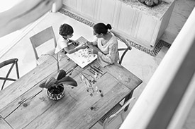 A mother and child at the dinner table drawing in a book.