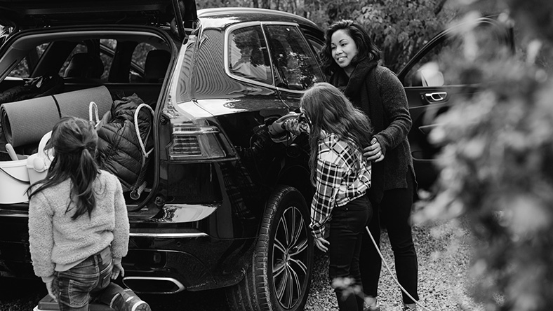 A mother loads the boot of her car with her two young daughters.
