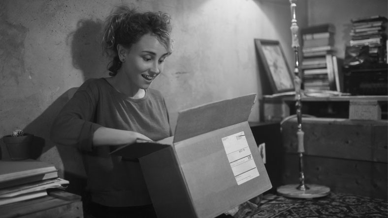 A young woman opening a box she ordered while online shopping.