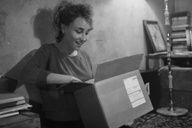 A young woman opening a box she ordered while online shopping.