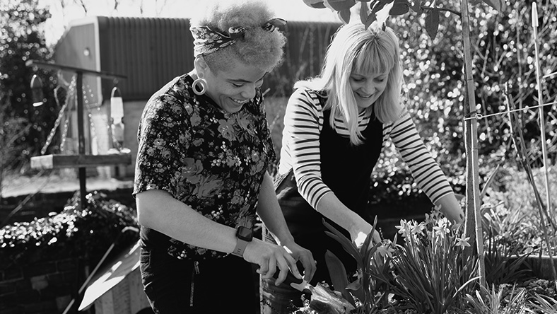 Two young women tend to their garden.