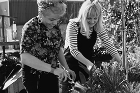Two young women tend to their garden.