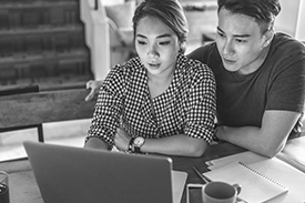 A couple sit at their kitchen table using a laptop, working out what they can claim as deductions on their tax return.