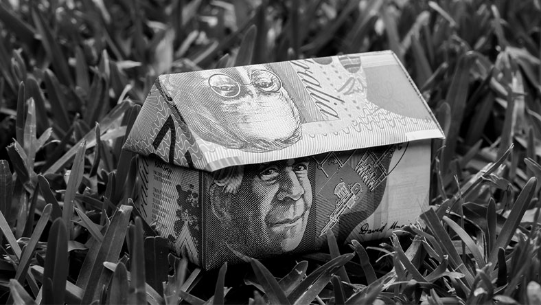 House shape made out of bank notes on grass