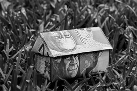 House shape made out of bank notes on grass