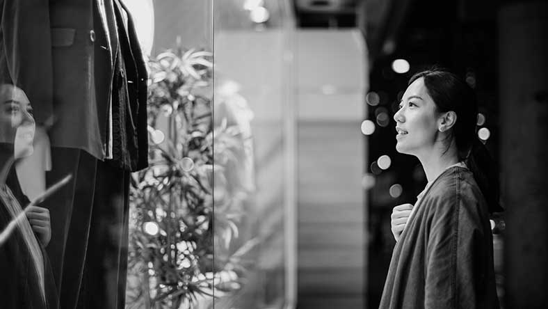 Woman looking in store window and smiling