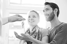 Young couple holding out hand to receive keys to new home