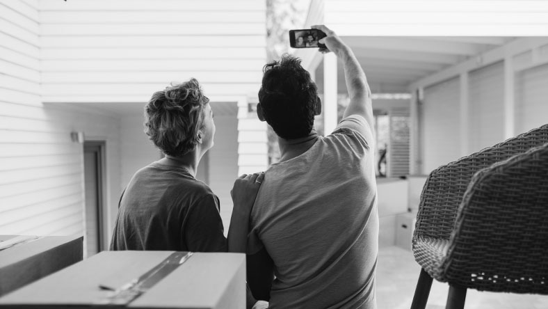 A young couple take a selfie in their new home.