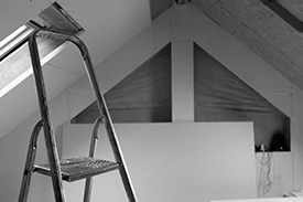 A step ladder is propped against the wall of a freshly painted room