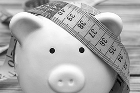 A tape measure rests on the head of a piggy bank.