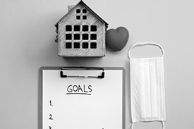 A model of a healthy home sits above a file with goals written on it and a mask.