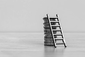 A small ladder leaning against a pile of coins.