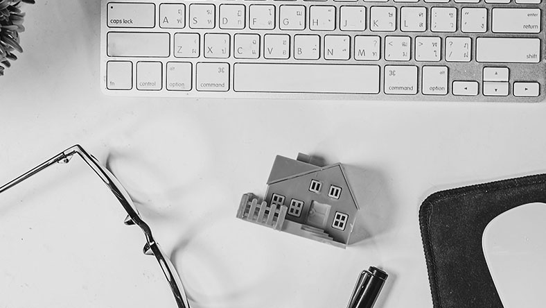 A small toy house sits beneath a computer keyboard.