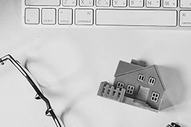 A small toy house sits beneath a computer keyboard.