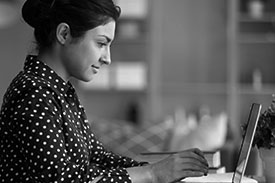 A young woman types on her laptop from her living room.