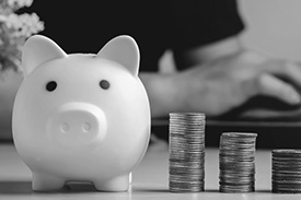 A piggy bank sits next to four stacks of coins.