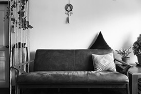 A brown couch sits beside a coffee table with two pot plants sitting on it.