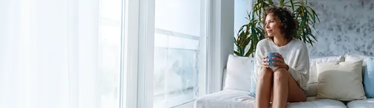 A young woman relaxes in their new home thanks to the Help to Buy Scheme.