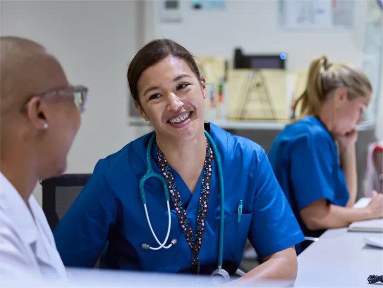 A group of healthcare professionals sit together at a workstation in a clinical environment